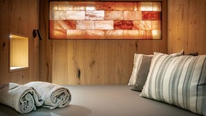 A room with wooden walls, a large window, a bed with striped bedding, and a rolled-up towel on the floor. - Hotel Rosa degli Angeli (Pejo)