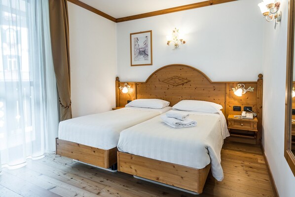 A double bed room with wooden headboard, two bedside tables with lamps, and a framed picture on the wall.