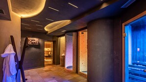 A spa area with a massage chair, a wall-mounted massage table, and a sauna. - Hotel Rosa degli Angeli (Pejo)