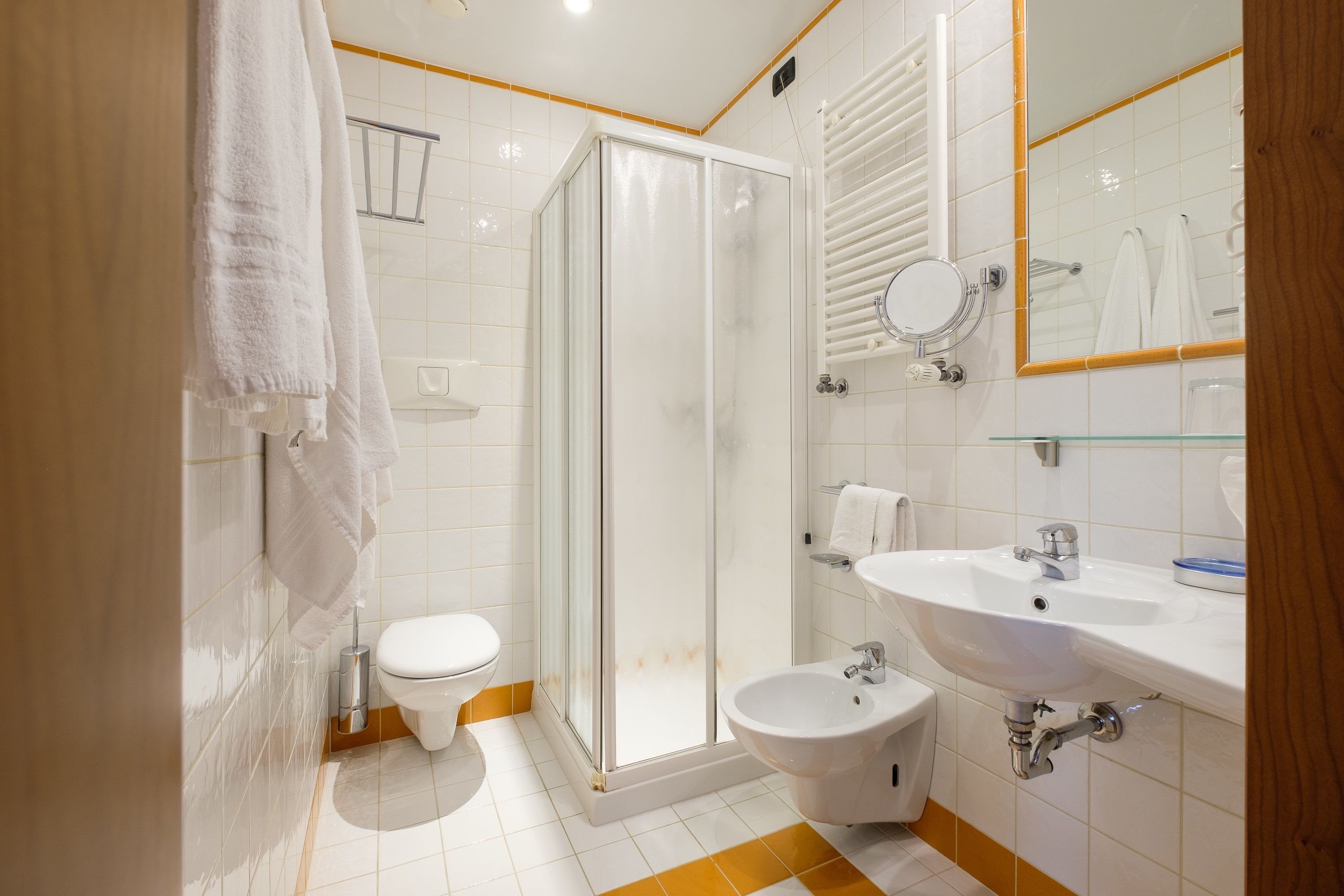 Un bagno moderno con doccia vetrata, un water, un bidet e un lavandino con specchio.