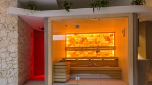 A sauna with a wooden bench and a glass wall.