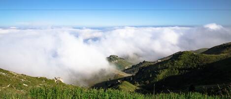 A mountainous landscape with a valley below, covered in clouds.