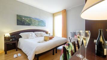 Ein Hotelzimmer mit einem Bett, einem Nachttisch, einem Tisch mit Gläsern und einer Flasche sowie einem Bild an der Wand.