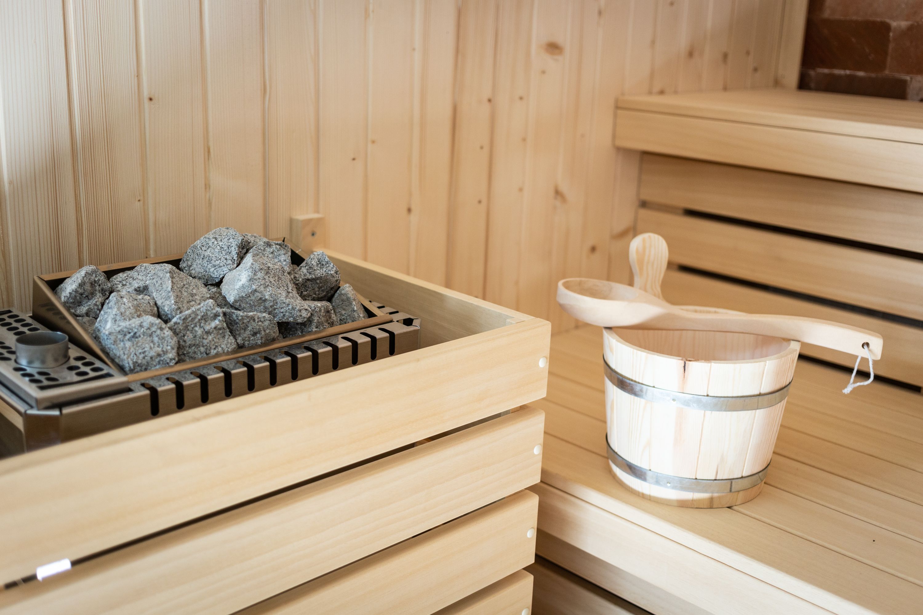 A wooden sauna with a stone tray and a wooden bucket.