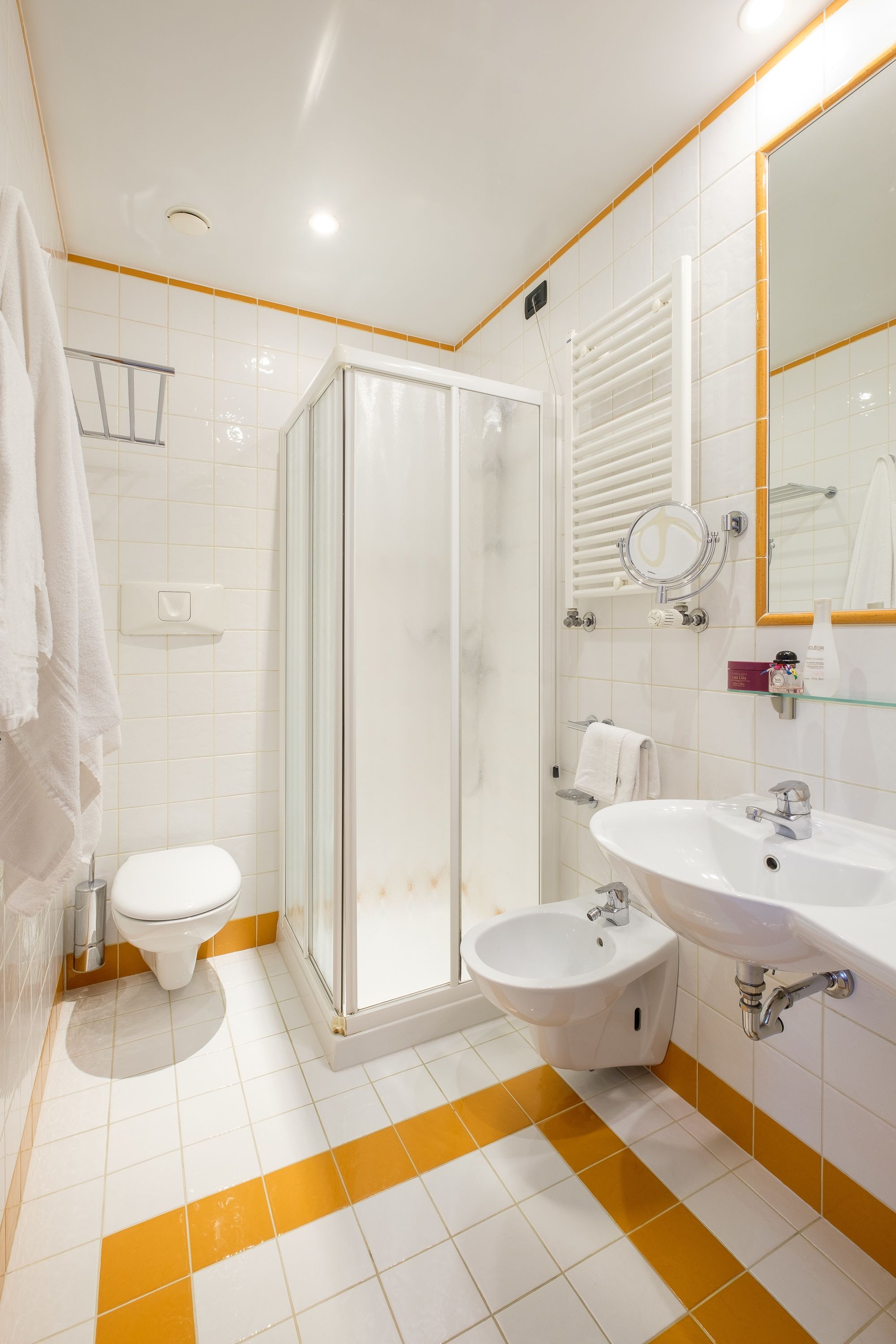 Un baño con ducha de vidrio, inodoro, bidé y lavamanos.