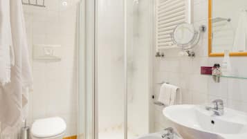 A bathroom with a glass-enclosed shower, a toilet, a bidet, and a sink.