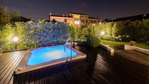 A swimming pool on a wooden deck with a view of a house in the background.
