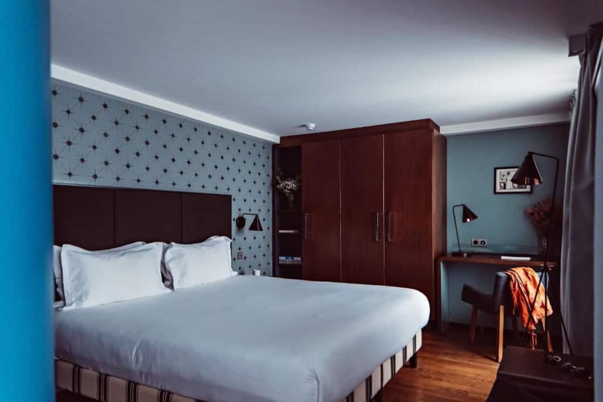 A bedroom with a bed, wardrobe, desk, and a wall with a star pattern.