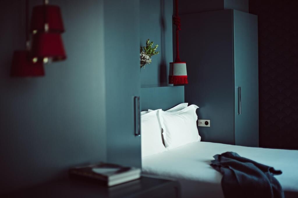 A hotel room with a bed, bedside table, and a wardrobe.