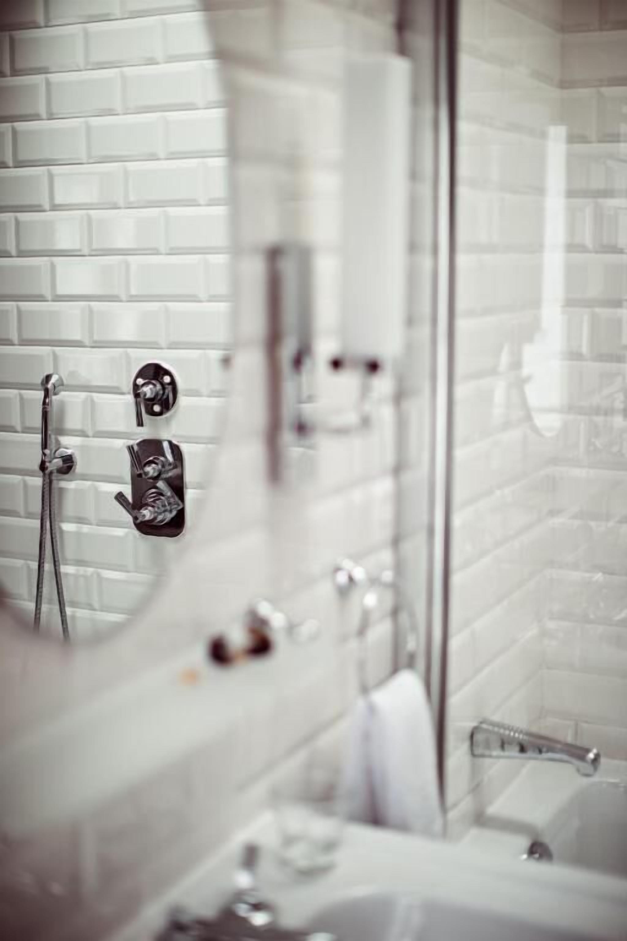 A bathroom with a white tiled wall, a glass shower enclosure, and a visible towel rack.
