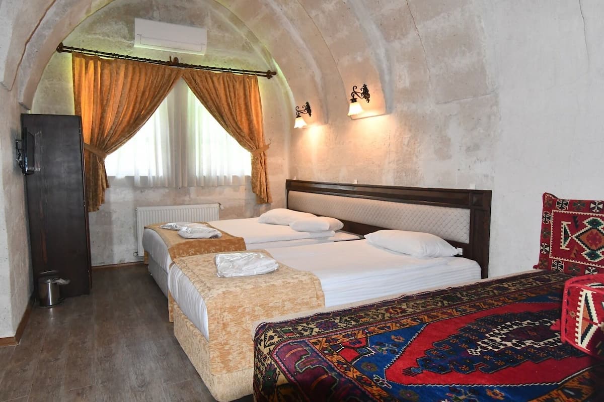 A room with two beds, a radiator, a wardrobe, and a patterned rug.