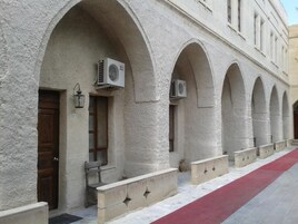 Un edificio con una hilera de ventanales arqueados y unidades de aire acondicionado instaladas en las paredes exteriores.