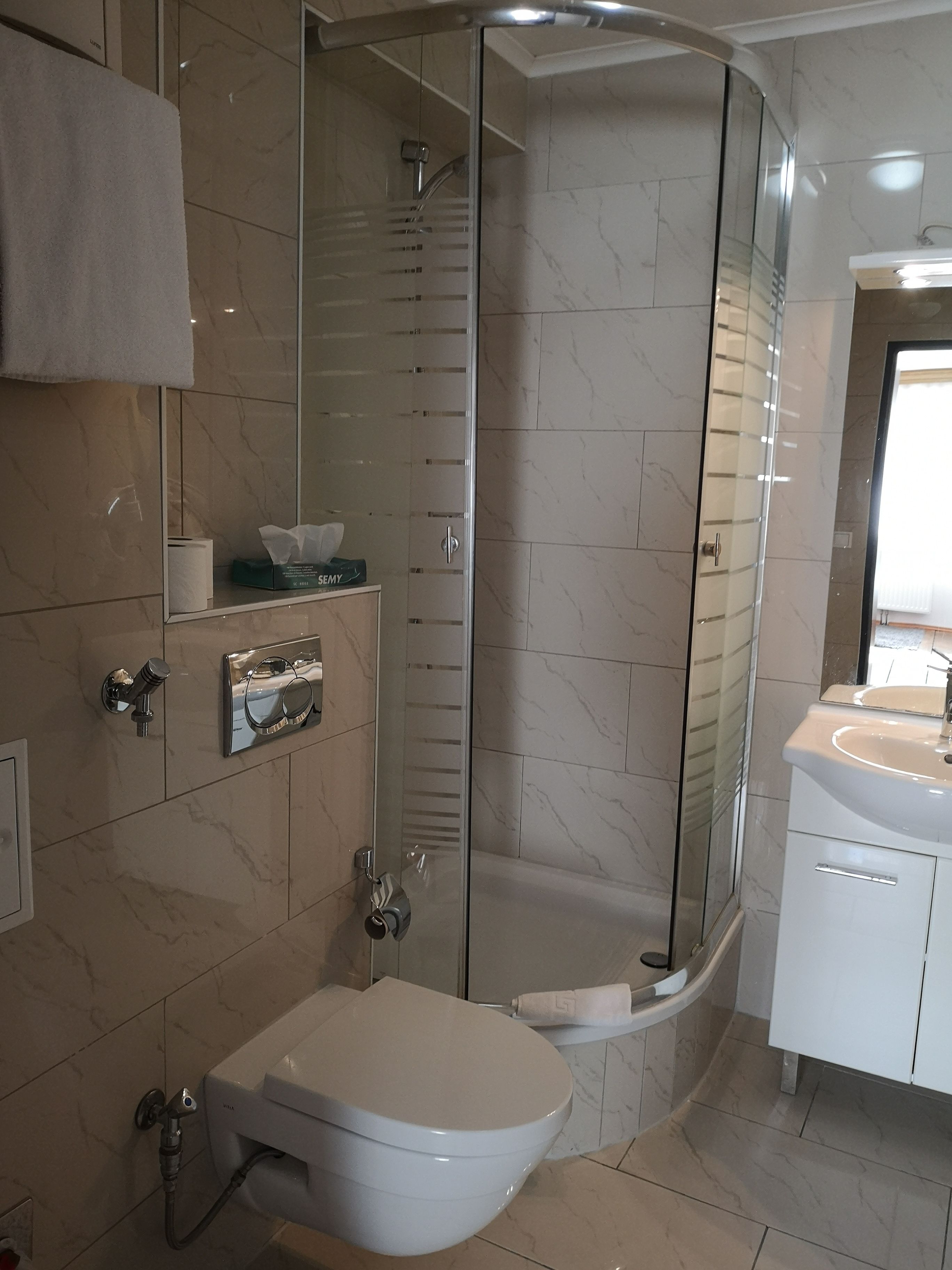 Une salle de bain moderne avec une douche à parois de verre, des toilettes et un lavabo.