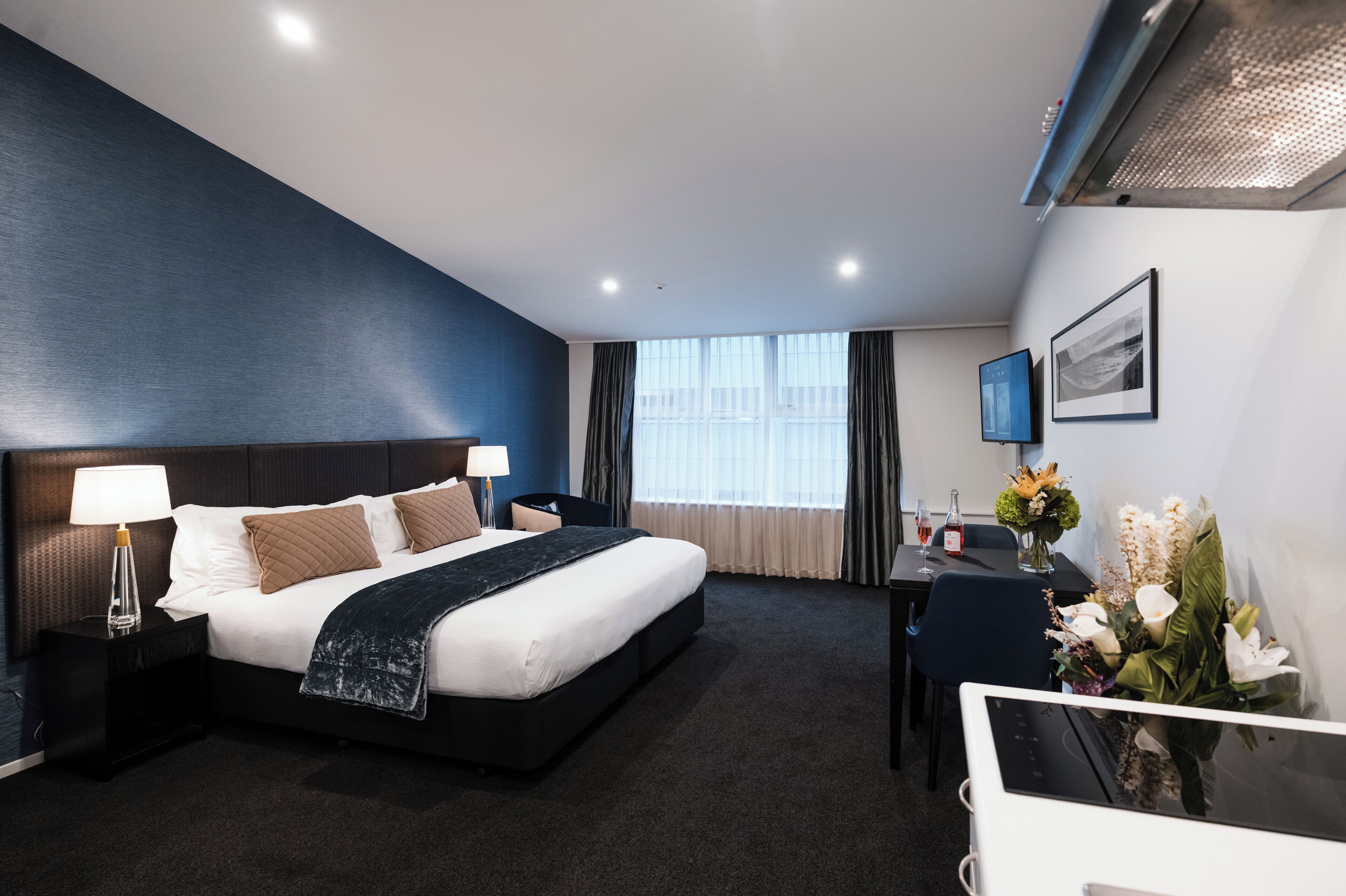 Een hotelkamer met een groot bed, een bureau, een stoel, een televisie en een raam met gordijnen.