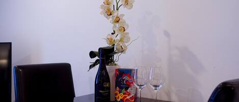 A table with a bottle of wine, two wine glasses, and a box of chocolates.