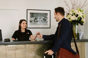Welcome to our reception area, featuring a framed cityscape, a reception desk, and a vase with white flowers.