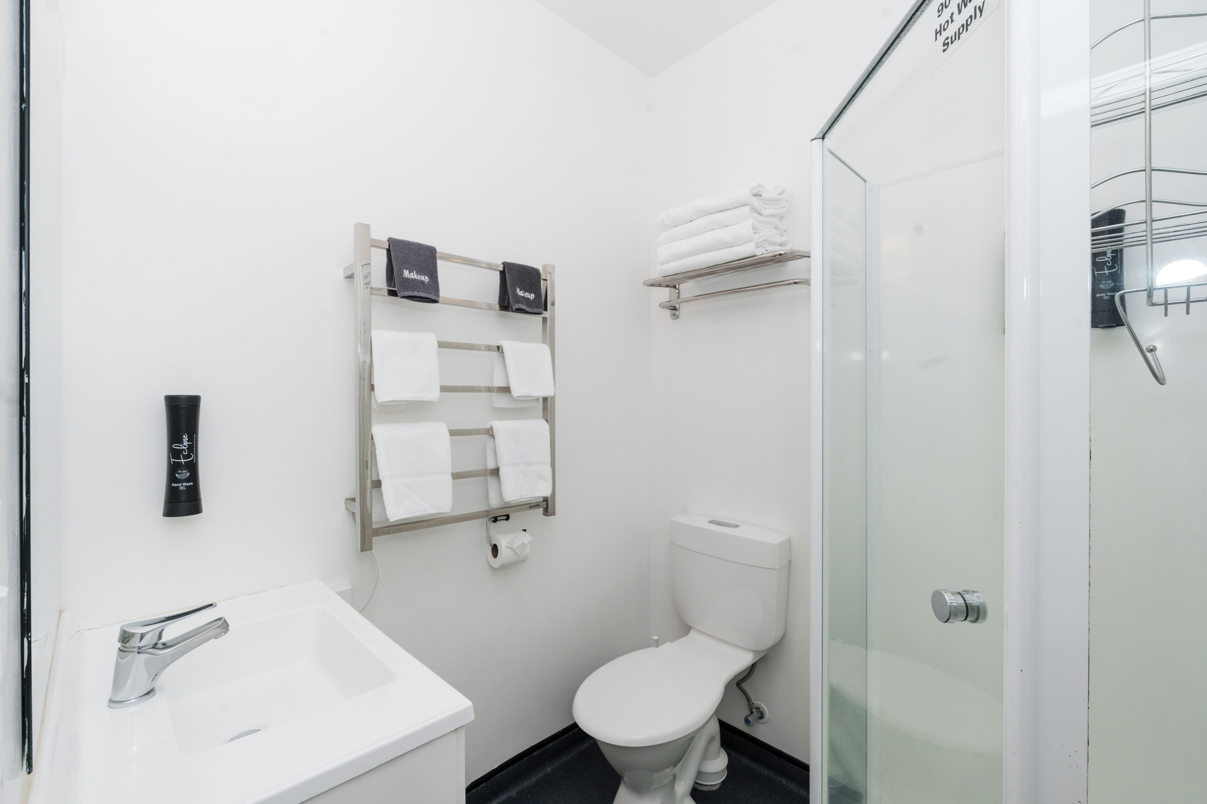 A modern bathroom with a white sink, toilet, and glass shower enclosure.
