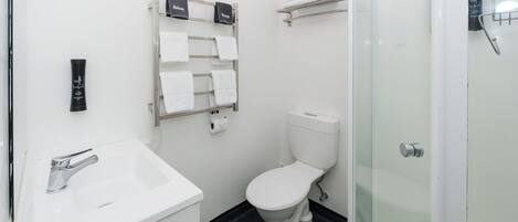 Un baño moderno con lavamanos, inodoro y cabina de ducha de vidrio.