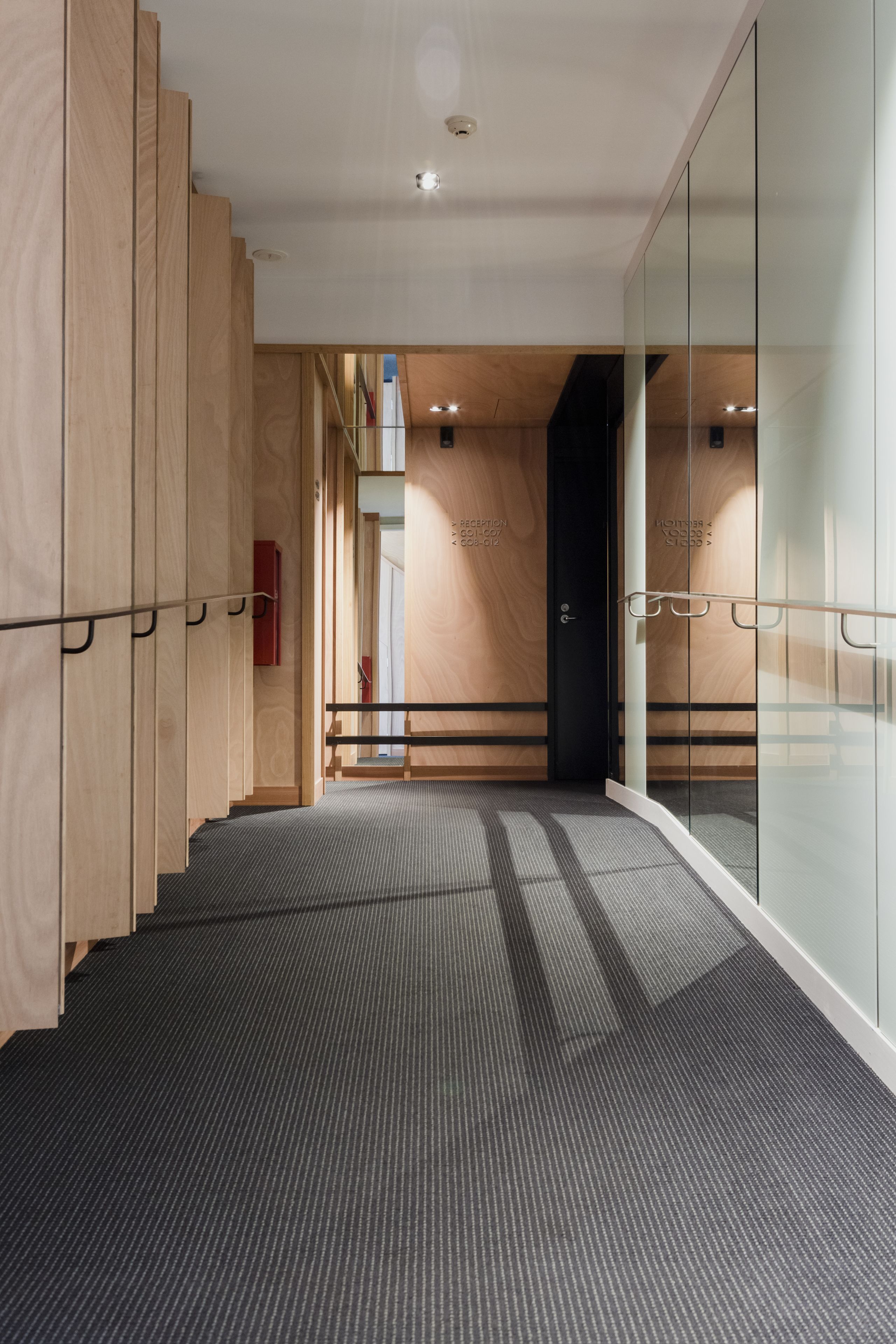 Un intérieur moderne avec des lambris en bois, un sol recouvert de moquette et une cloison en verre.