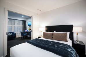 Habitación de hotel con una cama grande, dos lámparas de noche, un escritorio con una computadora portátil, una silla y un televisor.