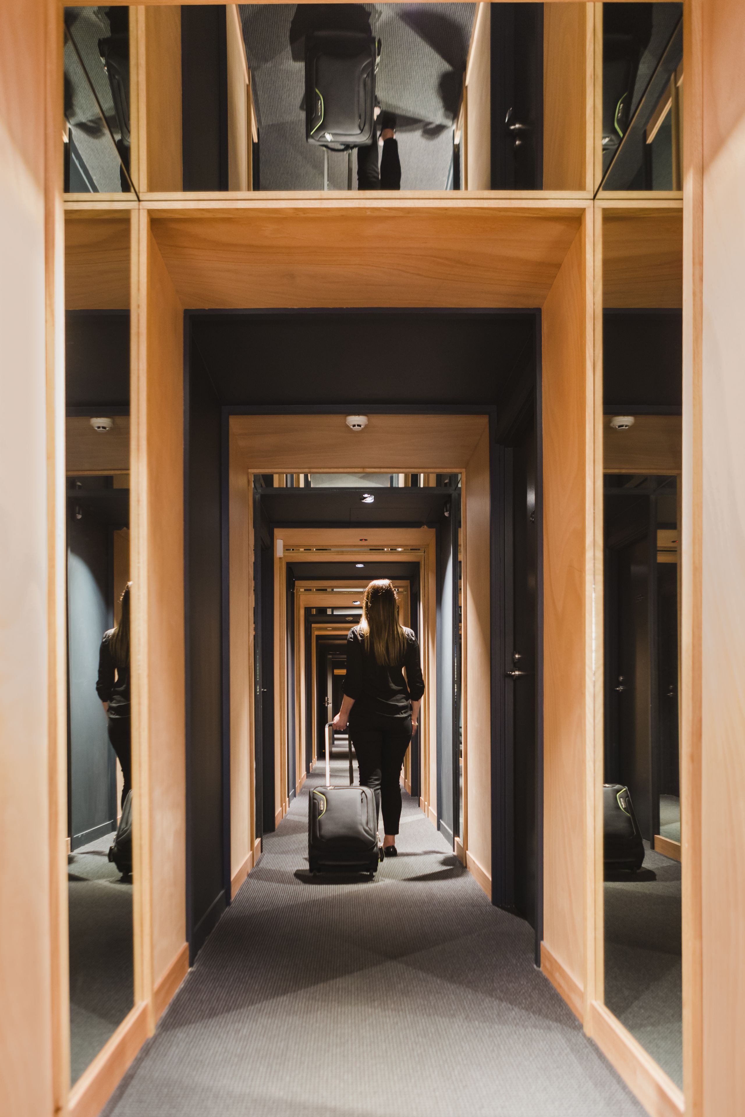 A hotel corridor with wooden paneling and a carpeted floor.