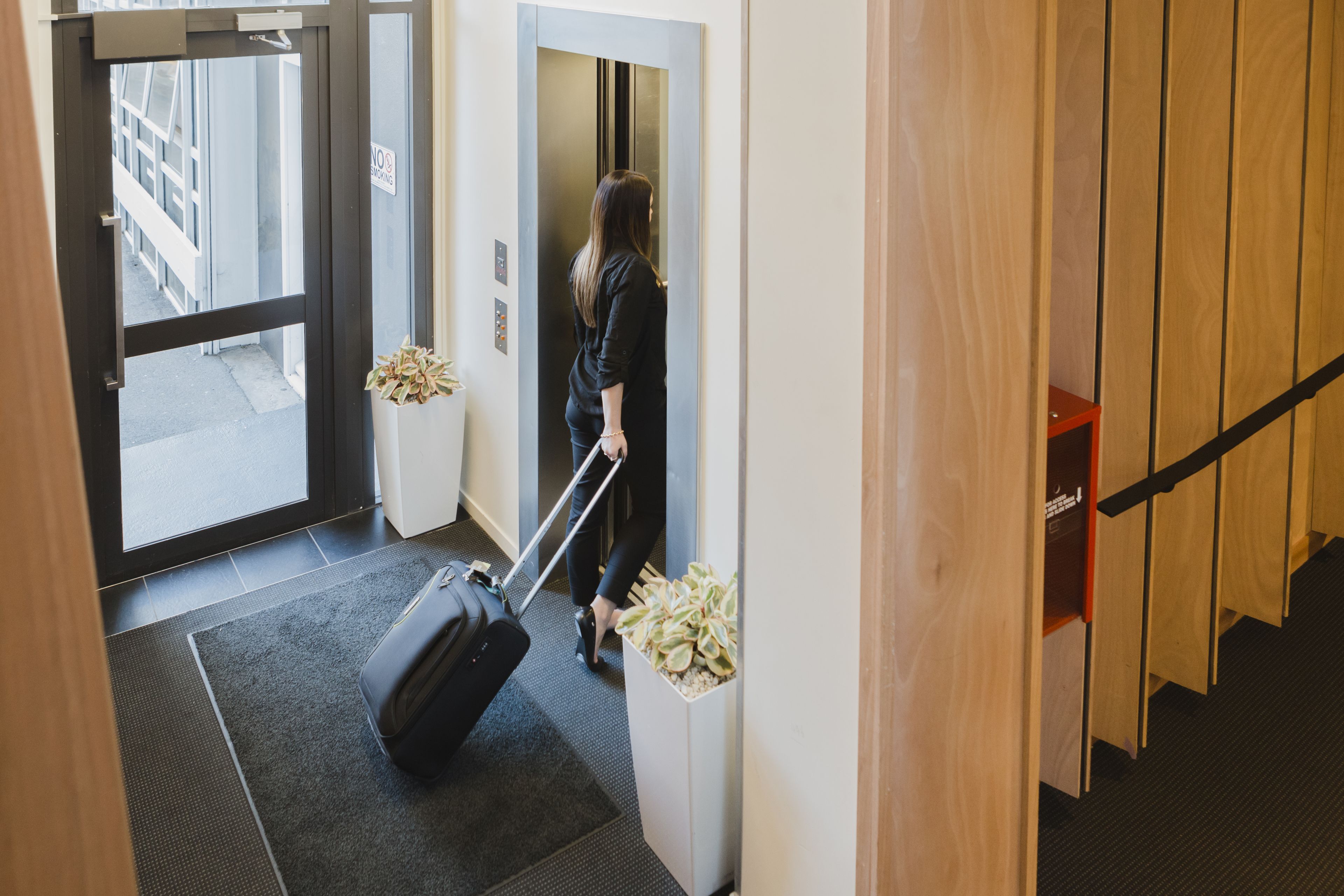 A person with luggage entering a hotel room through a door.