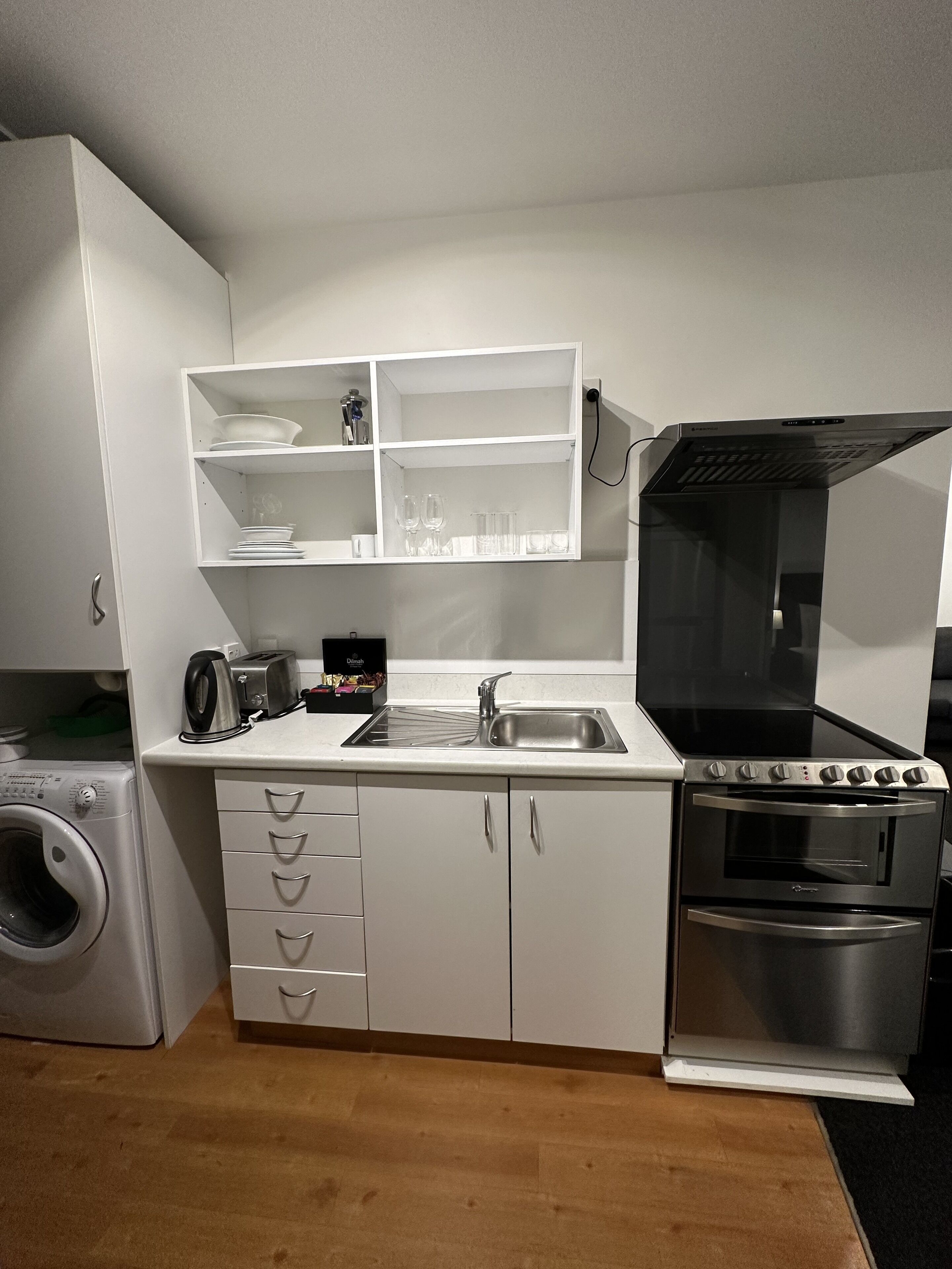 Une cuisine compacte équipée d’un lave-linge intégré, d’un four et d’un four à micro-ondes.