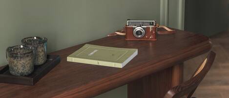 A wooden desk with a vintage camera, a book, and two cups on a tray.
