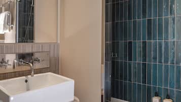 Un baño con un lavamanos blanco, un espejo, una ducha y una bañera.
