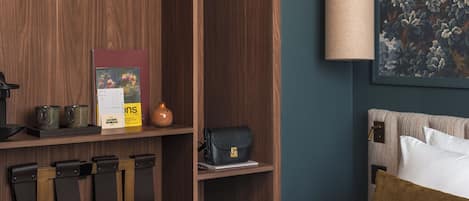 Un dormitorio con cama, armario de madera, lámpara colgante y un cuadro floral.