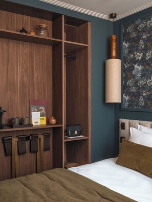 A bedroom with a bed, a wooden wardrobe, a hanging lamp, and a floral painting. - Lazare Nomade (Paris)