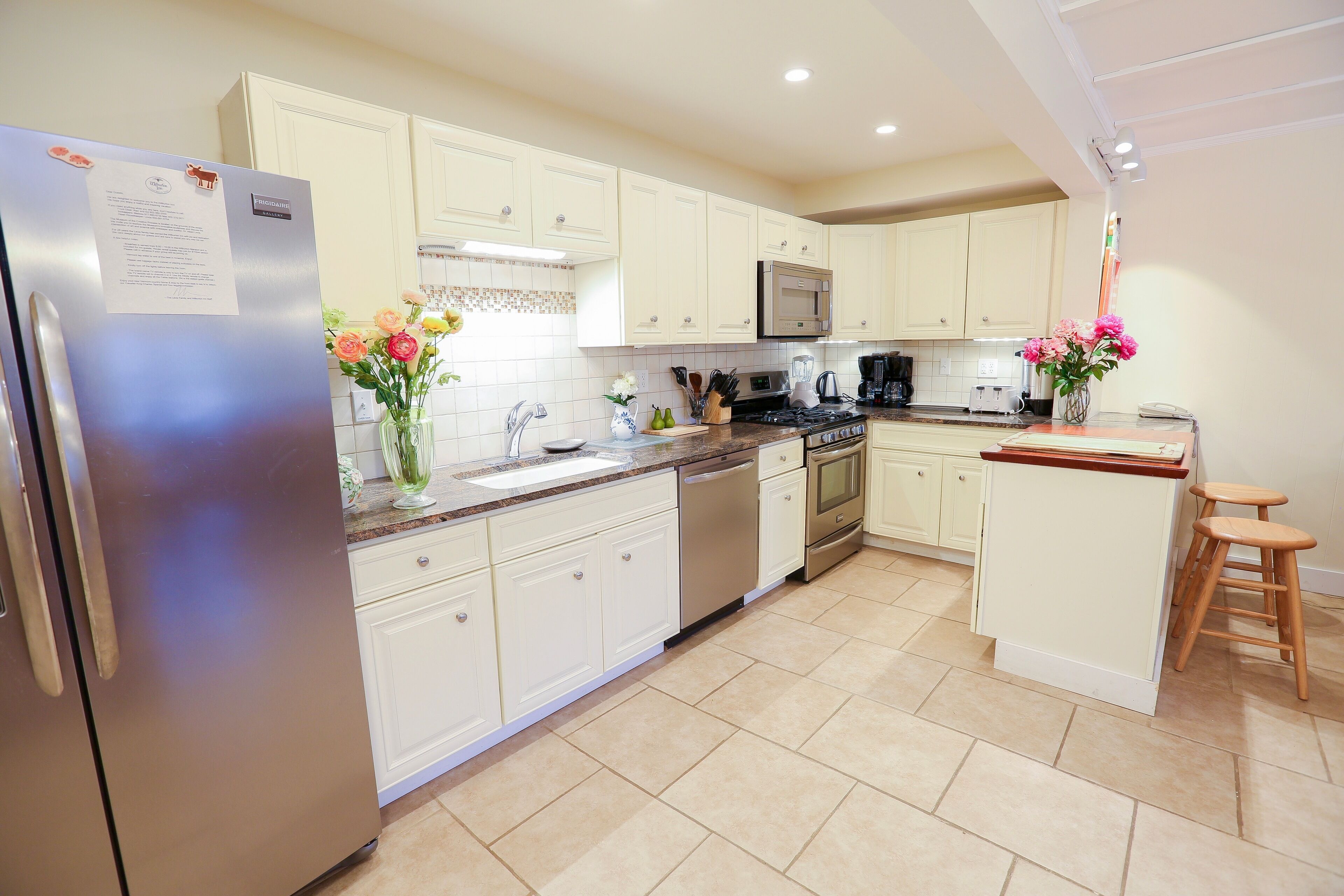 A modern kitchen with white cabinets, stainless steel appliances, and a central island with stools.