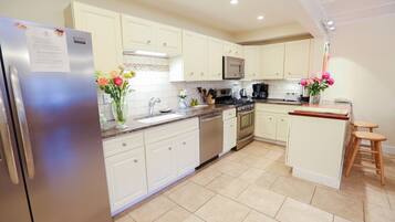 A modern kitchen with white cabinets, stainless steel appliances, and a central island with stools.