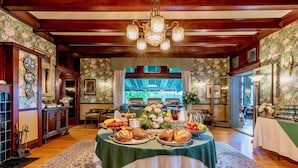 A dining area with a buffet table, floral wallpaper, and a chandelier.