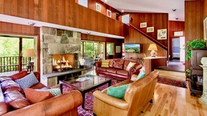 A spacious living room with a stone fireplace, leather sofas, and a television.