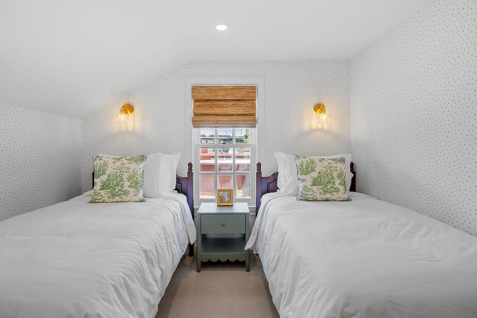 Un dormitorio con dos camas, una ventana con vistas e iluminación en la pared.