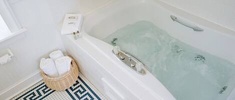 A bathroom with a bathtub, a wicker basket with towels, and a checkered floor.