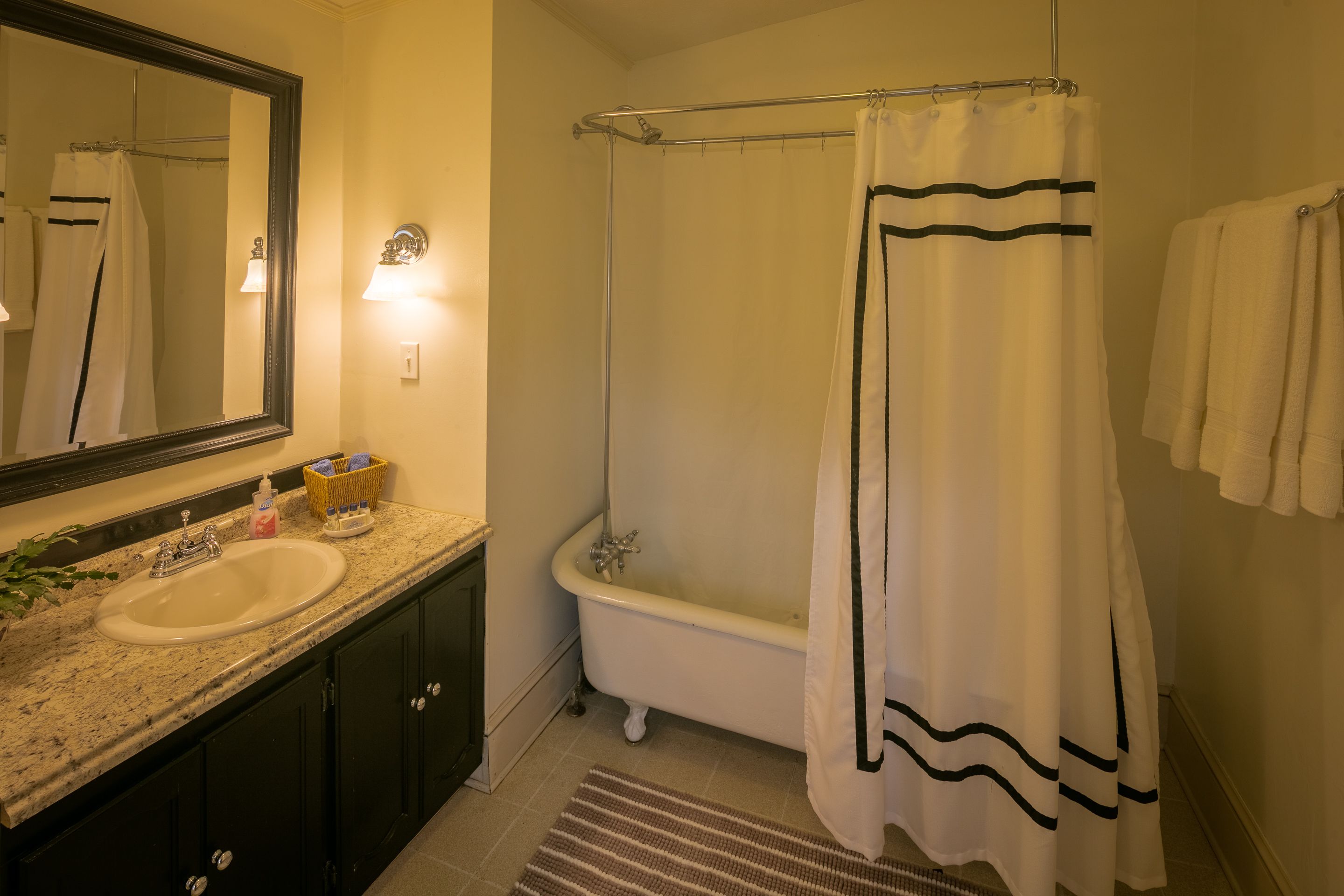 A bathroom with a sink, mirror, bathtub, and a shower curtain.