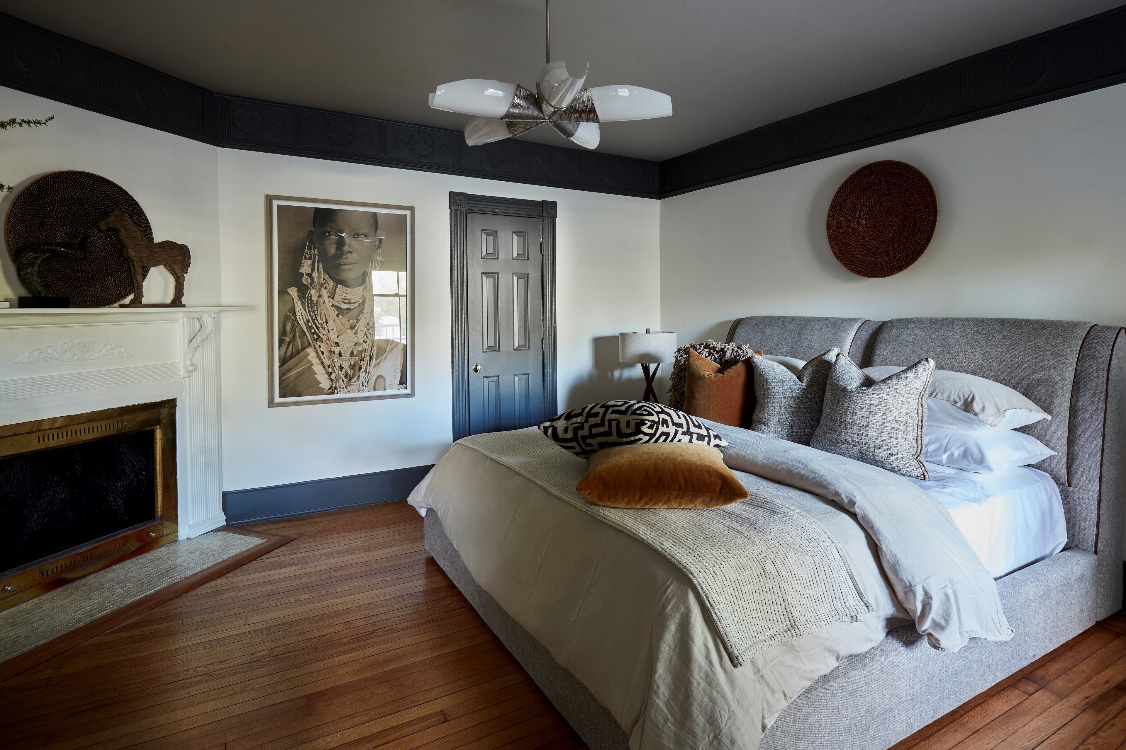 A bedroom with a large bed, a fireplace, and a ceiling fan.