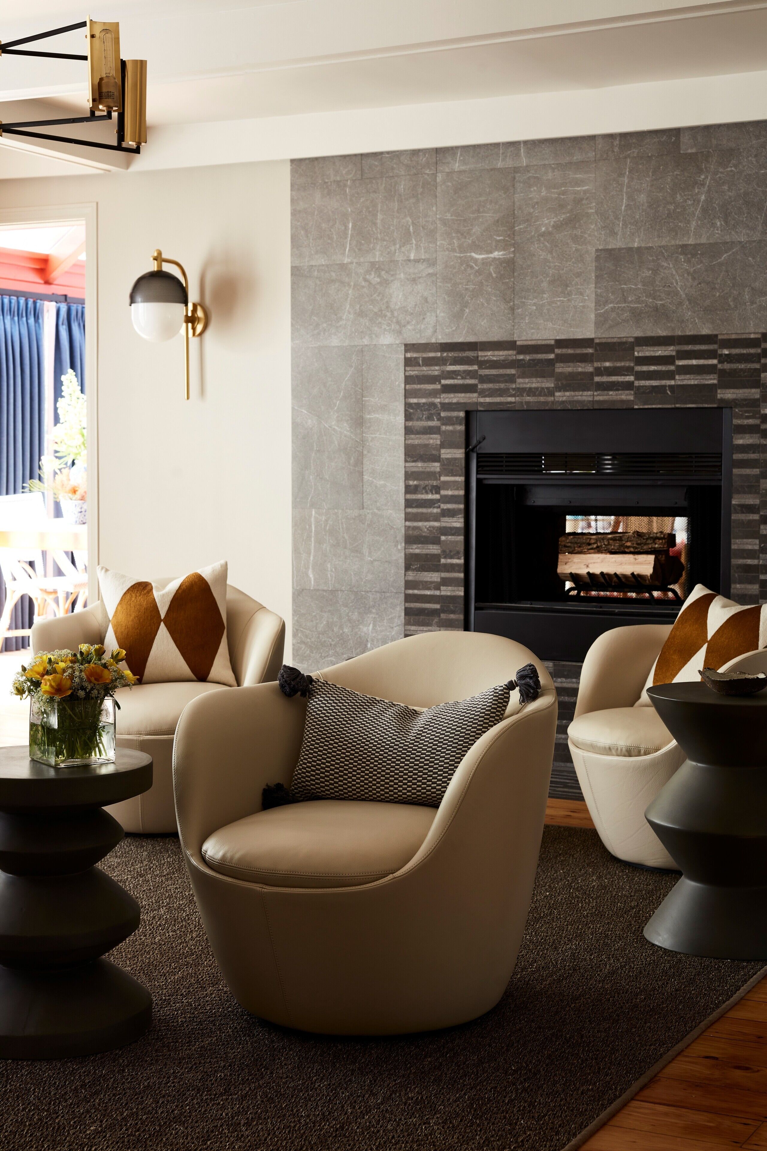 Een moderne woonkamer met een open haard, leren banken en een decoratieve vaas.