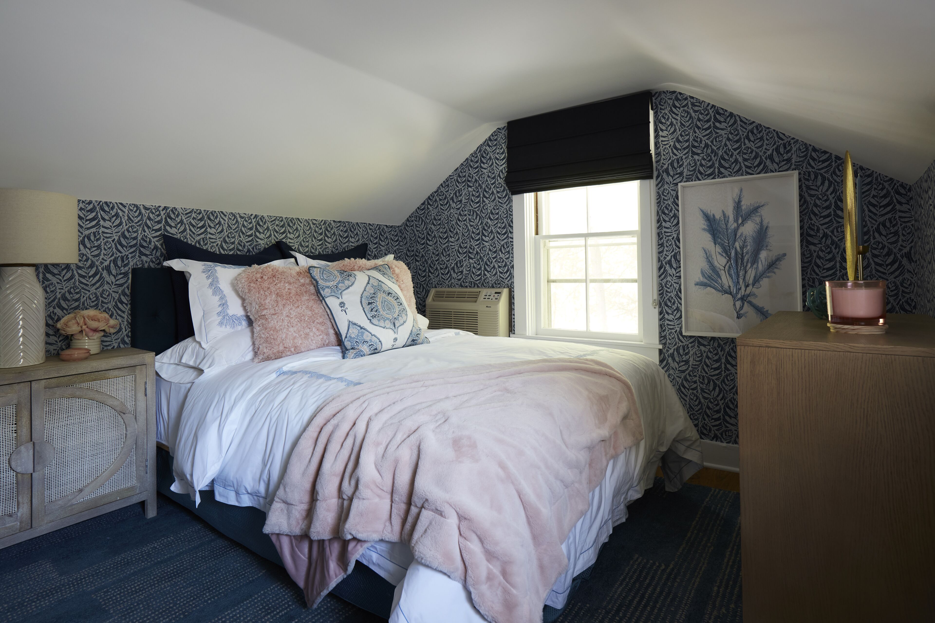 A bedroom with a bed, bedside table, and a window.