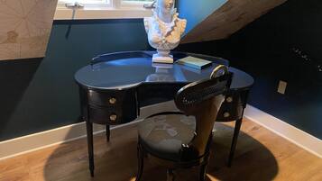 A room with a desk, chair, and a bust sculpture.
