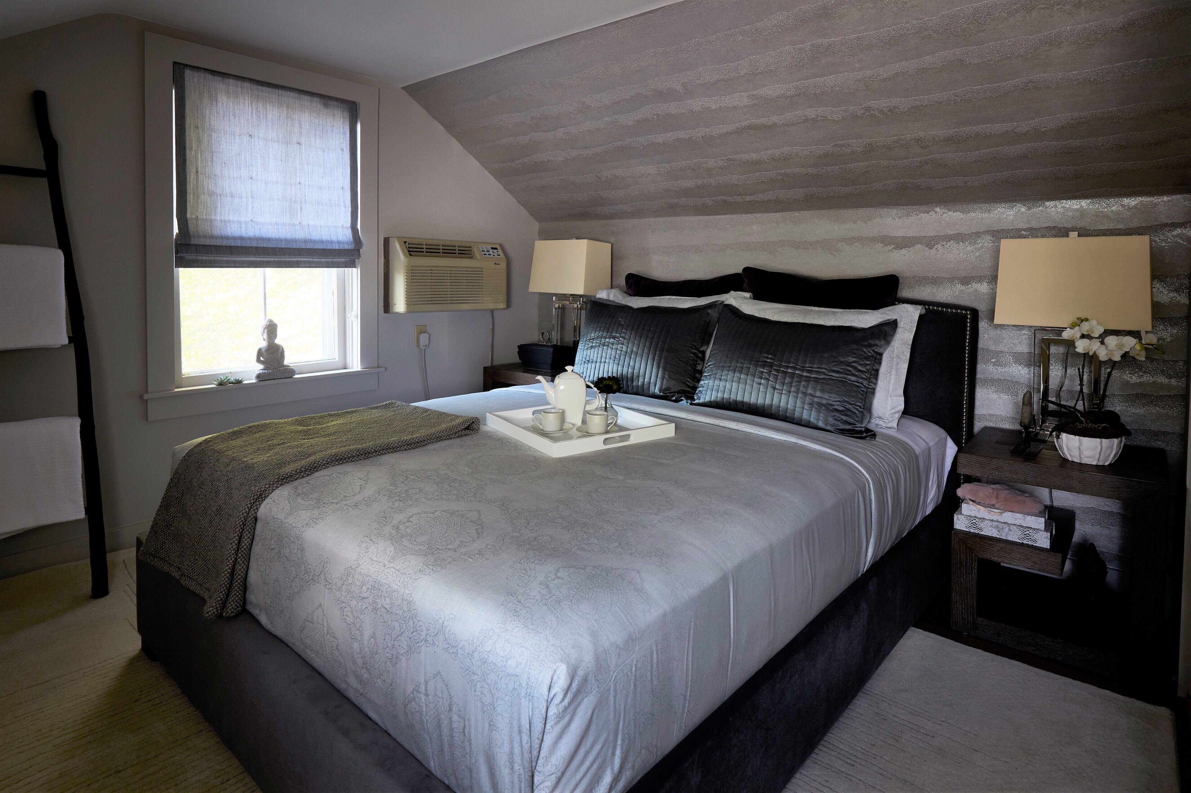 Slaapkamer met een groot bed, twee nachtkastjes, een raam met uitzicht en een plafond met structuur.