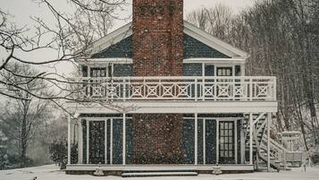 A snow-covered building with a brick chimney, white railings, and a porch.