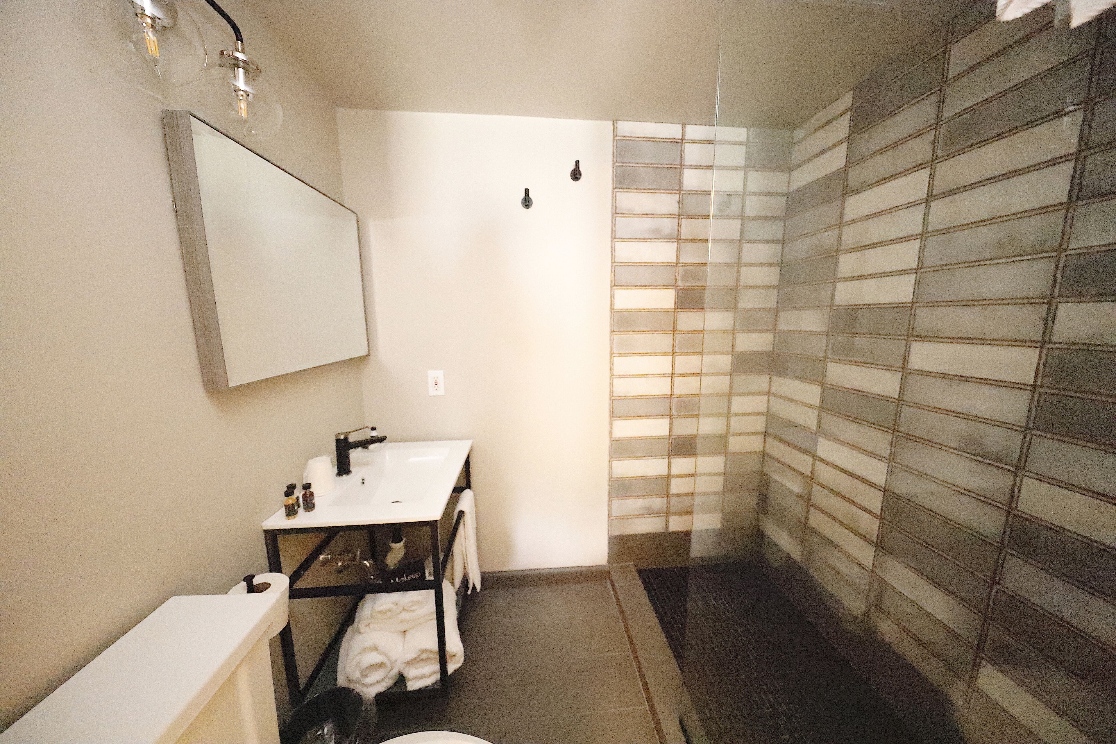 A small bathroom with a white sink, mirror, and shower.