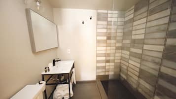 A small bathroom with a white sink, mirror, and shower.