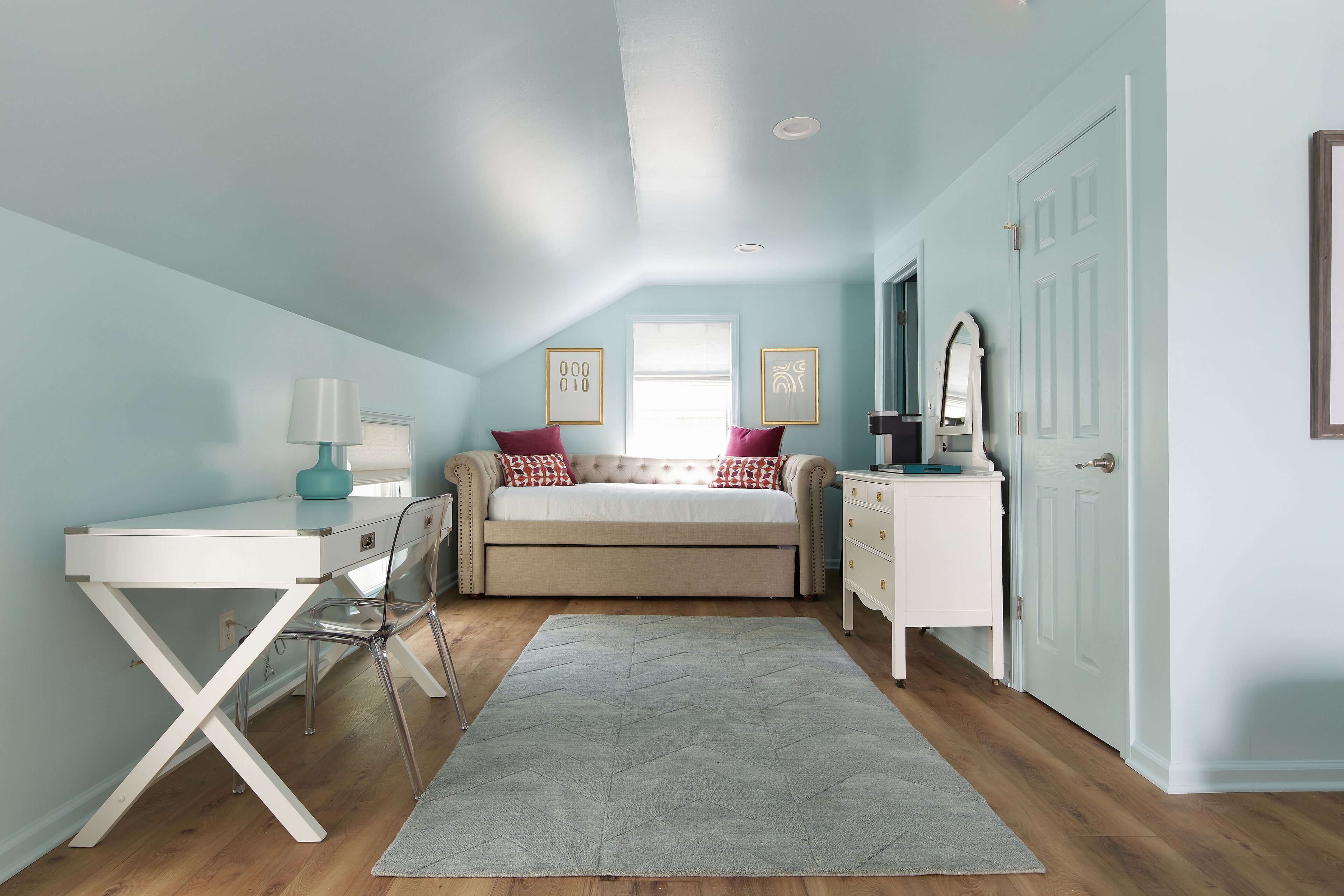 Une chambre à coucher comprenant un lit, un bureau, une chaise, une commode et une porte.