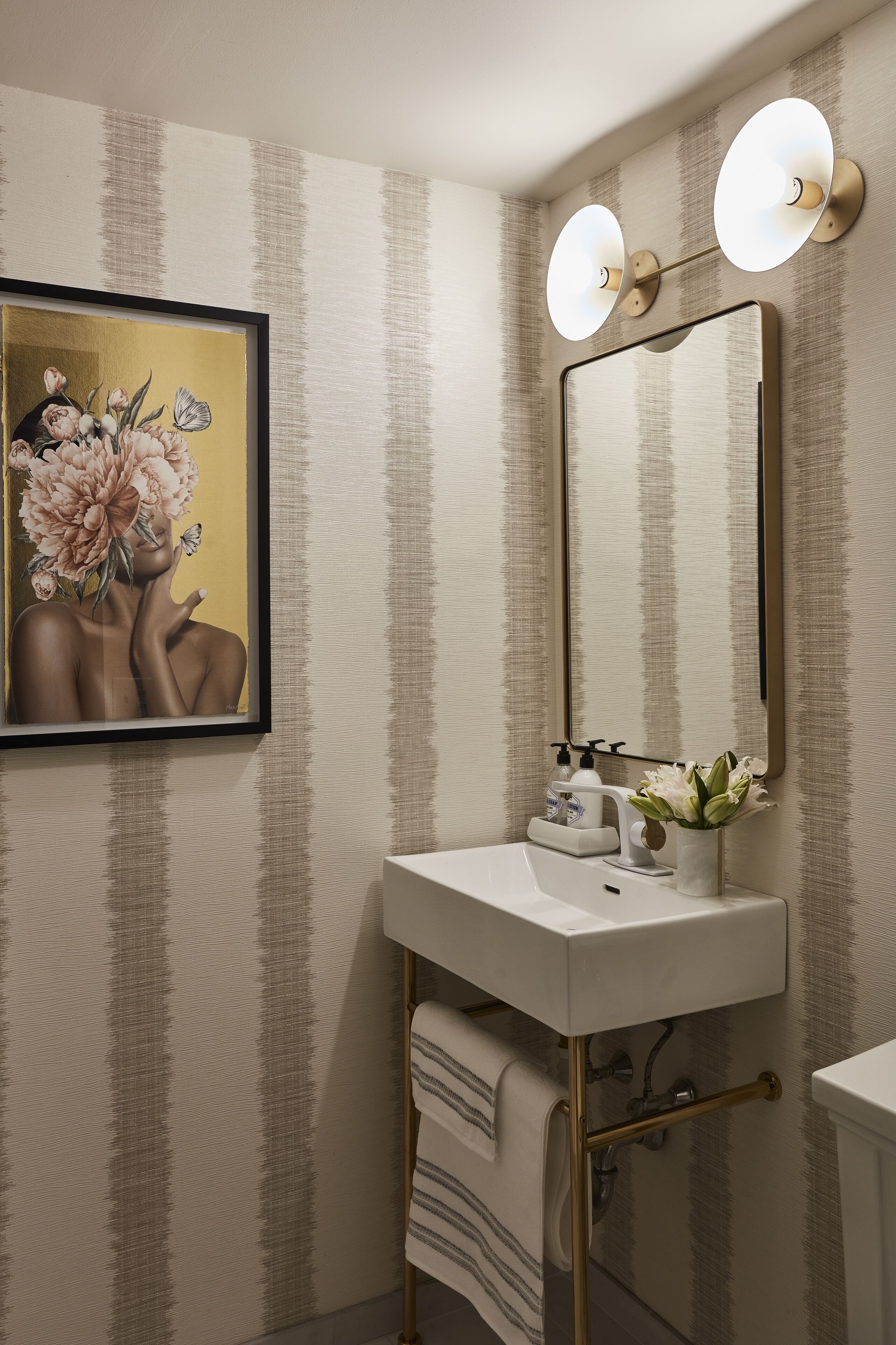 A bathroom with a white sink, a large mirror, and two wall-mounted lights.
