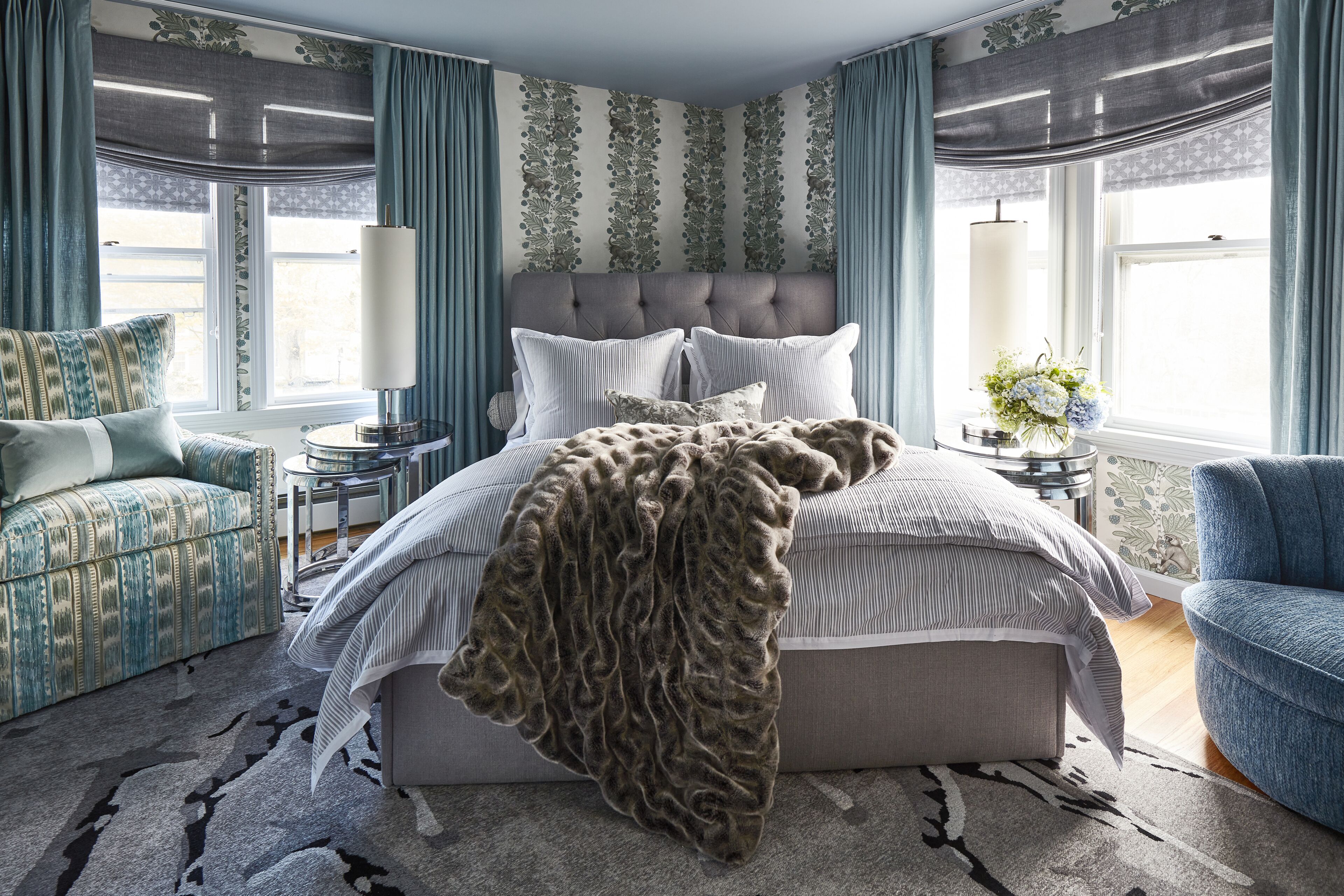 A bedroom with a large bed, two bedside tables, a chair, and a window with curtains.