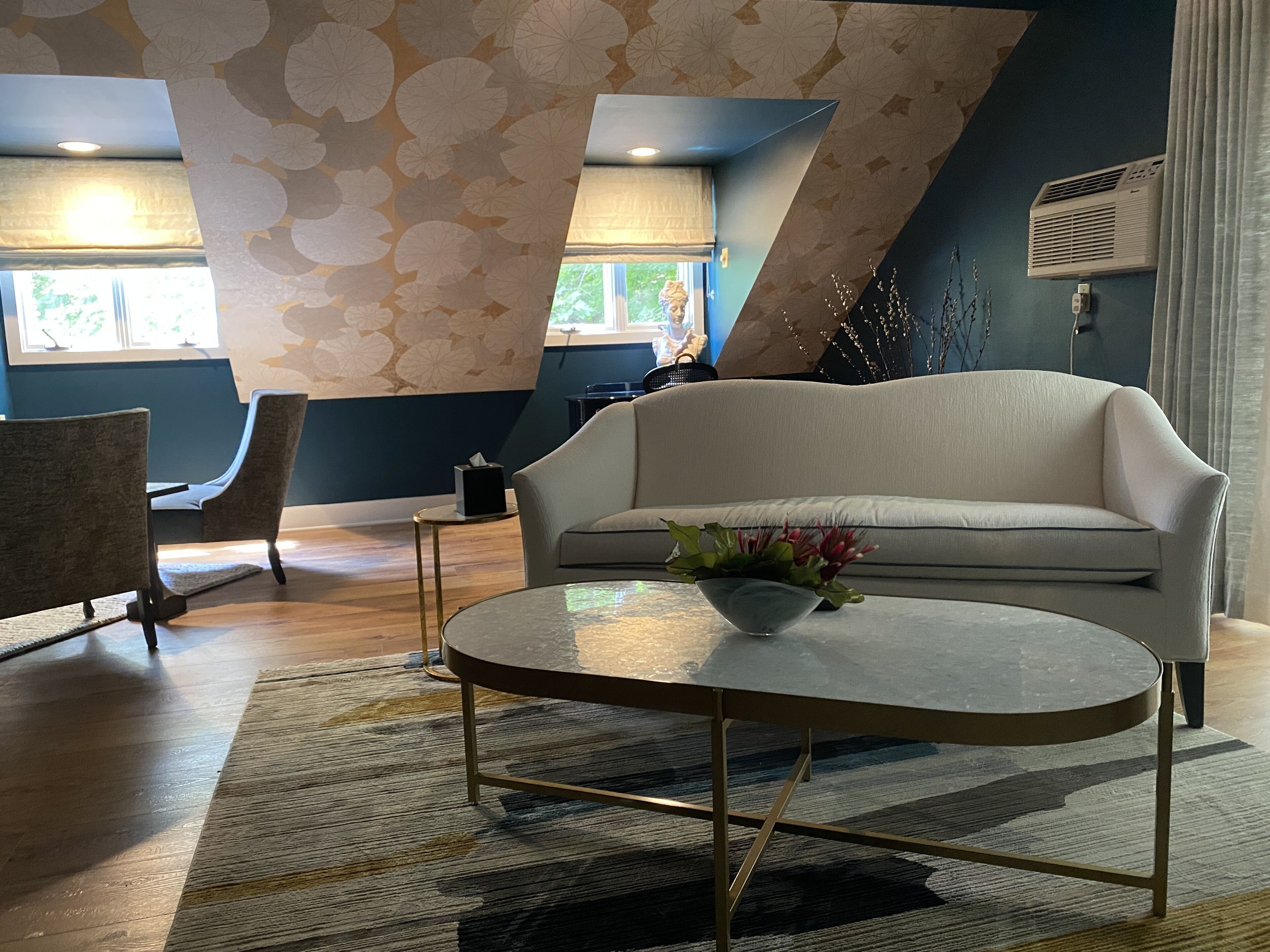 Una sala de estar moderna con un sofá, una mesita redonda y una alfombra estampada.